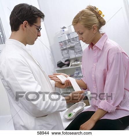 Male doctor bandaging patient's hand View Large Photo Image Picture - Male doctor bandaging patient's hand . Fotosearch