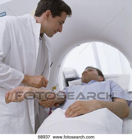 Male doctor giving injection to patient on MRI scanbed View Large Photo Image Stock Photo - Male doctor giving injection to patient on MRI scanbed . Fotosearch