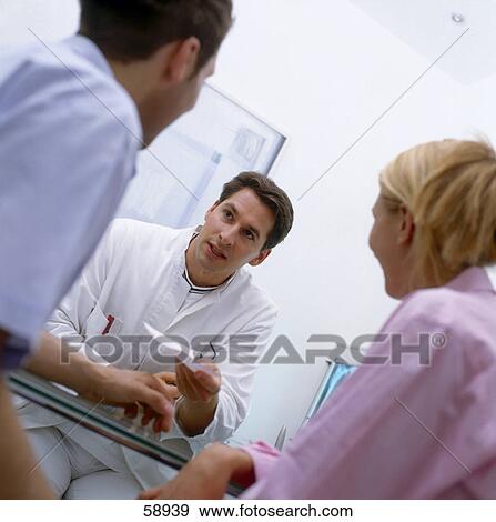 Male doctor talking to young couple View Large Photo Image Stock Photo - Male doctor talking to young couple . Fotosearch