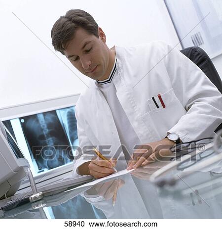 Stock Image - Male doctor writing on paper in hospital . Fotosearch