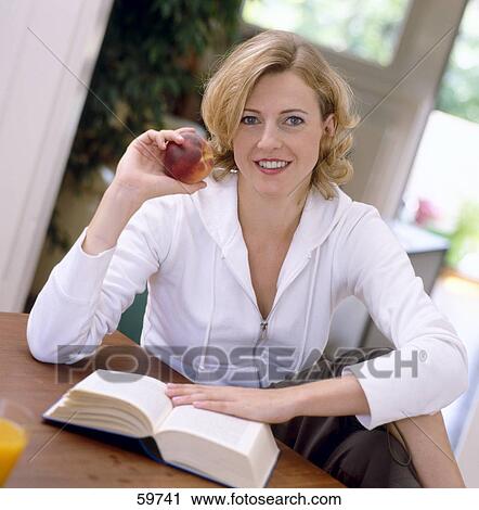 Stock Image - Portrait of a young woman holding a peach and smiling . Fotosearch