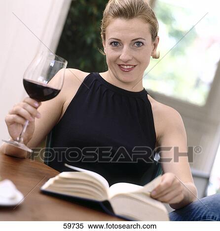 Stock Photography - Portrait of a young woman holding glass of red wine and smiling . Fotosearch