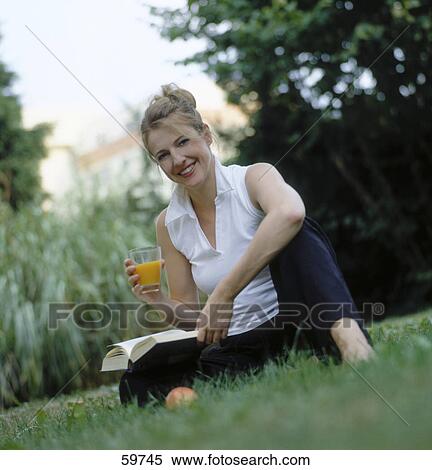 Portrait of a young woman sitting in garden and holding glass of orange juice View Large Photo Image Stock Photography - Portrait of a young woman sitting in garden and holding glass of orange juice . Fotosearch