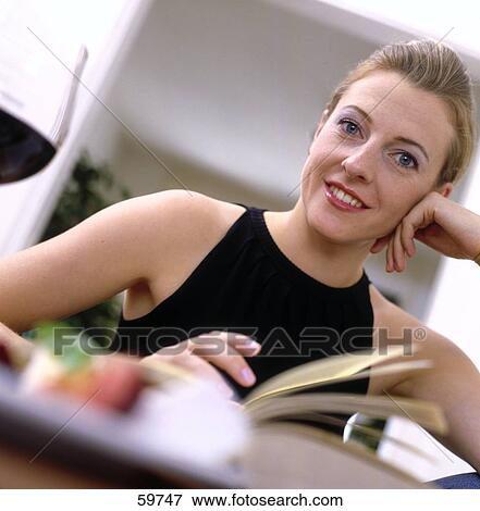 Stock Photo - Portrait of a young woman smiling at table . Fotosearch