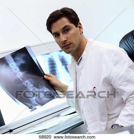 Stock Image - Portrait of male doctor holding x-ray image . Fotosearch