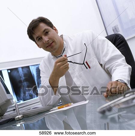 Stock Photograph - Portrait of male doctor sitting in hospital . Fotosearch