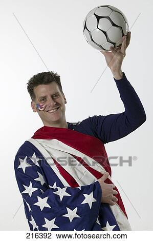 Stock Image - Portrait of male soccer fan holding soccer ball and smiling . Fotosearch