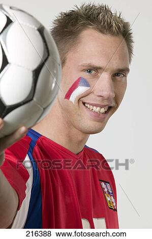 Stock Photo - Portrait of male soccer fan holding soccer ball and smiling . Fotosearch
