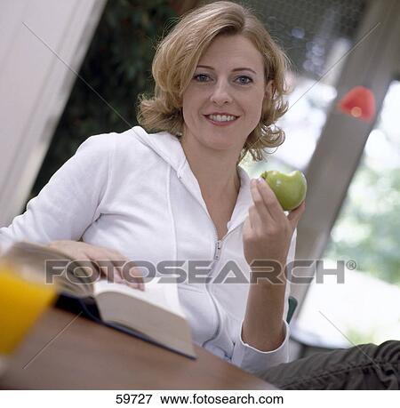 Portrait of young woman holding apple and smiling View Large Photo Image Stock Photo - Portrait of young woman holding apple and smiling . Fotosearch