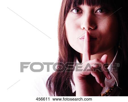 Stock Image - Portrait of young woman with her finger on her lips . Fotosearch