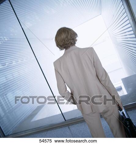 Rear view of businesswoman standing in front of window View Large Photo Image Stock Photography - Rear view of businesswoman standing in front of window . Fotosearch