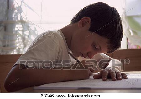 Stock Photograph - Side profile of boy writing on notebook . Fotosearch