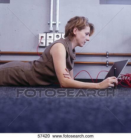 Side profile of businesswoman lying on the floor and using laptop View Large Photo Image Stock Image - Side profile of businesswoman lying on the floor and using laptop . Fotosearch