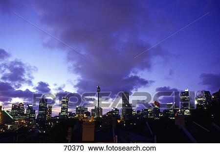 Stock Image - Skyscrapers lit up at dusk in city, Sydney, New South Wales, Australia . Fotosearch