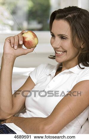 Stock Image - Smiling woman holding an apple . Fotosearch