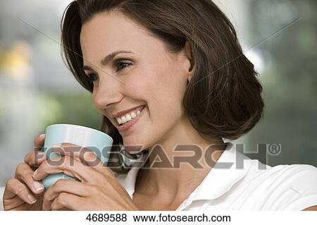 Smiling woman holding cup of coffee View Large Photo Image Stock Photo - Smiling woman holding cup of coffee . Fotosearch