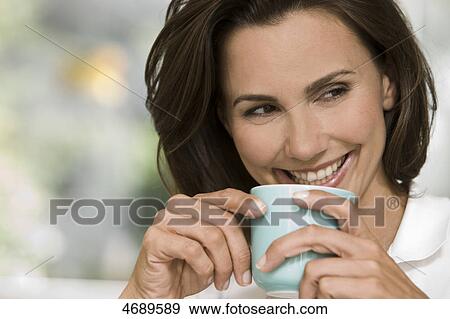 Smiling woman holding cup of coffee View Large Photo Image Stock Photo - Smiling woman holding cup of coffee . Fotosearch