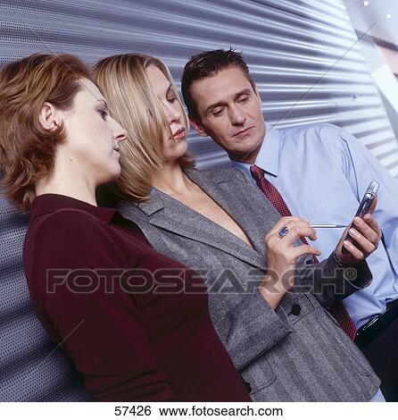 Three employees looking at handheld View Large Photo Image Stock Photograph - Three employees looking at handheld . Fotosearch
