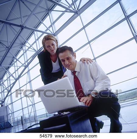 Stock Photo - Two businesspeople with laptop, low angle view . Fotosearch