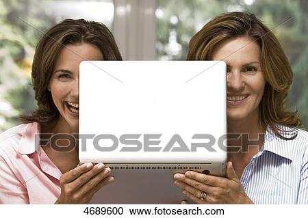 Stock Image - Two happy women holding laptop . Fotosearch