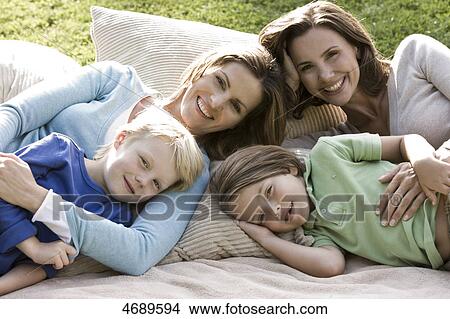 Picture - Two happy women with two children on blanket outdoors . Fotosearch