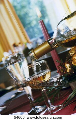 Stock Image - Wine being poured from bottle into glass . Fotosearch