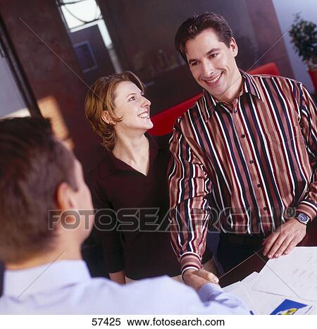 Stock Photography - Woman looking at his husband shaking hands with businessman . Fotosearch