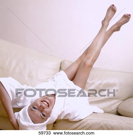 Stock Image - Woman relaxing on sofa, elevated view . Fotosearch
