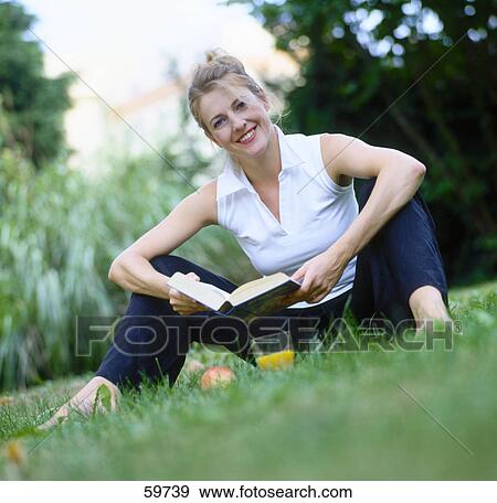 Woman sitting on meadow and reading a book View Large Photo Image Stock Photo - Woman sitting on meadow and reading a book . Fotosearch