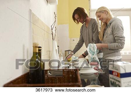 Stock Image - Young couple doing the dishes in kitchen . Fotosearch