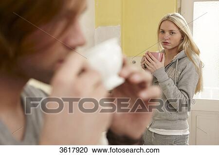 Stock Image - Young couple drinking coffee in kitchen . Fotosearch
