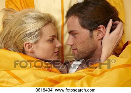 Picture - Young couple in bed looking at each other . Fotosearch