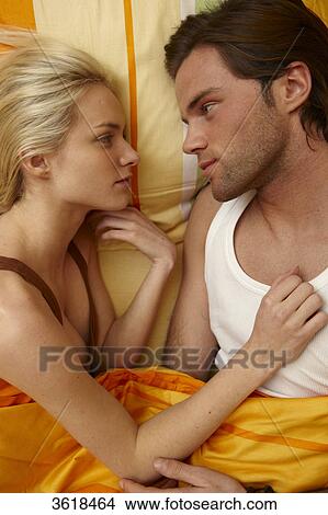 Picture - Young couple in bed looking at each other . Fotosearch