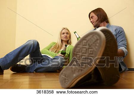 Young couple sitting on floor drinking beer View Large Photo Image Stock Photo - Young couple sitting on floor drinking beer . Fotosearch