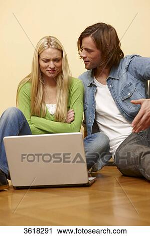 Young couple using laptop on floor View Large Photo Image Stock Image - Young couple using laptop on floor . Fotosearch