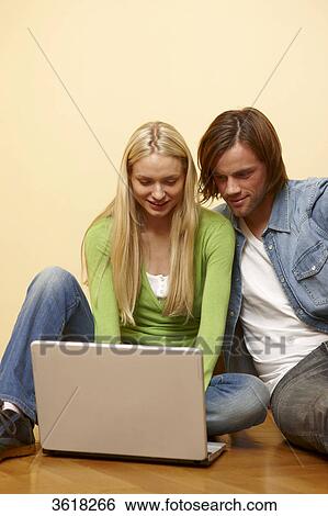 Young couple using laptop on floor View Large Photo Image Stock Photograph - Young couple using laptop on floor . Fotosearch