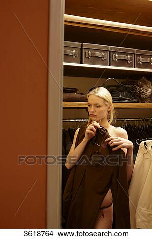 Young woman choosing blouse from wardrobe View Large Photo Image Picture - Young woman choosing blouse from wardrobe . Fotosearch