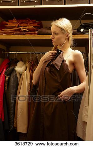 Stock Photo - Young woman choosing blouse from wardrobe . Fotosearch