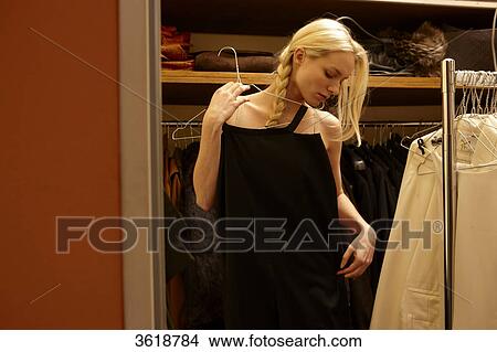 Young woman choosing dress from wardrobe View Large Photo Image Picture - Young woman choosing dress from wardrobe . Fotosearch