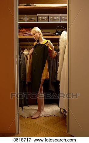 Young woman choosing dress from wardrobe View Large Photo Image Stock Photo - Young woman choosing dress from wardrobe . Fotosearch