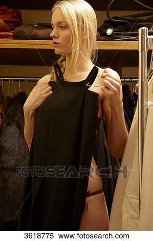 Stock Photography - Young woman choosing dress from wardrobe . Fotosearch