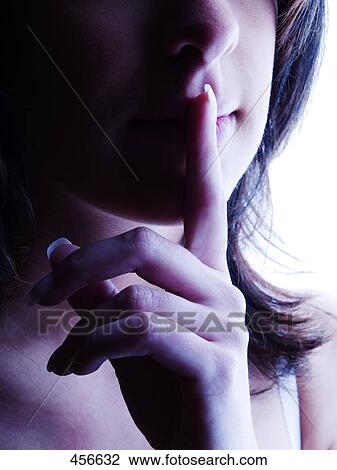 Stock Image - Young woman holding finger on lips . Fotosearch