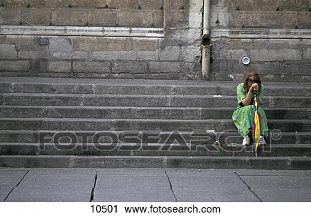 Stock Image - Young woman sitting on step and looking sad . Fotosearch