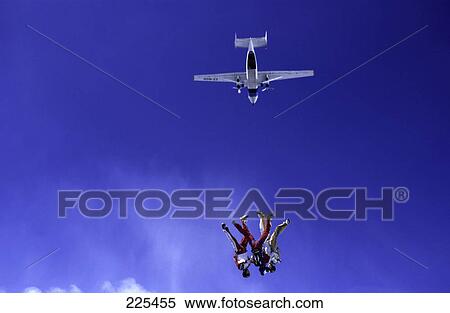 Stock Photography - Airplane flying over two people parachuting mid air . Fotosearch