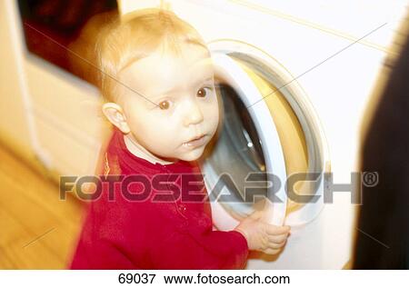 Stock Photo - Boy standing beside washing machine, blurred . Fotosearch