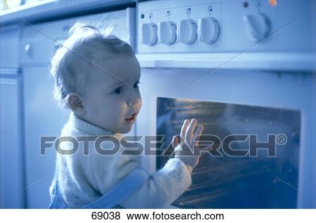 Stock Photo - Boy touching oven, blurred . Fotosearch