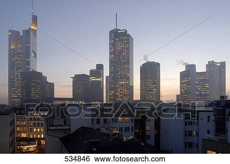 Stock Photograph - Buildings in city lit up against evening sky, Frankfurt, Germany . Fotosearch
