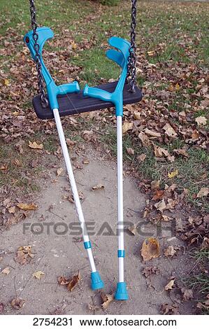 Stock Image - Close-up of crutches on chain swing . Fotosearch