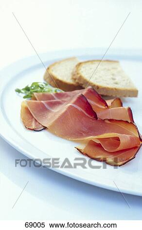 Stock Photography - Close-up of prosciutto and parsley with slices of breads on plate . Fotosearch