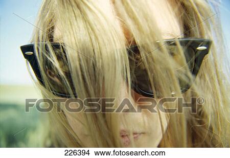 Close-up of woman with tousled hair wearing sunglasses View Large Photo Image Picture - Close-up of woman with tousled hair wearing sunglasses . Fotosearch